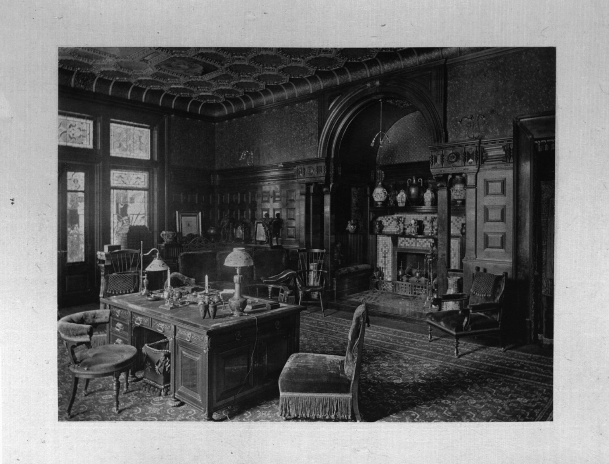 The wood-paneled library of the J. Pierpont Morgan House, lit by electric lamps.